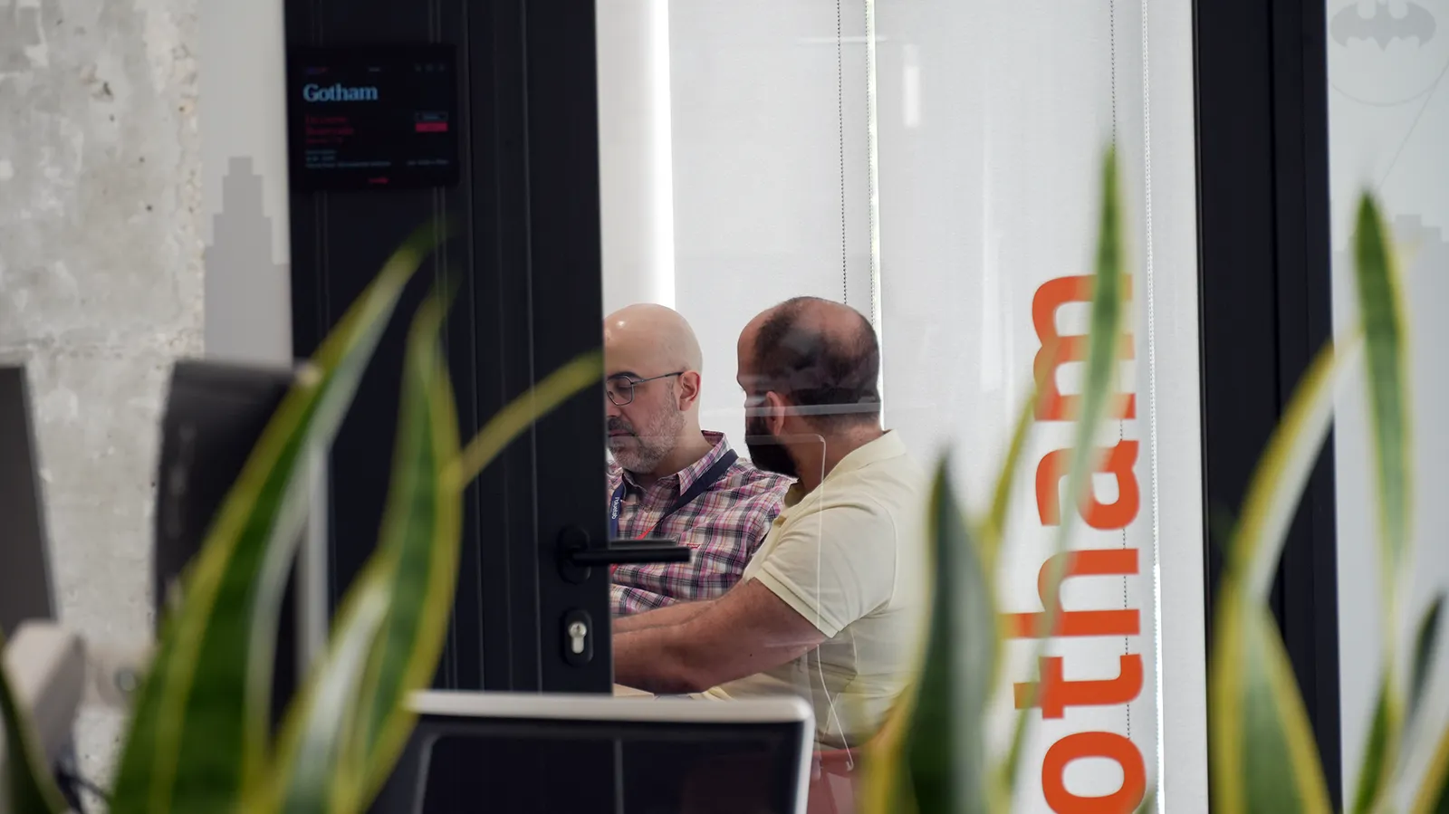 Colaboradores de Bluetab reunidos en una sala de trabajo dentro de una oficina moderna con elementos naturales y ambiente tecnológico